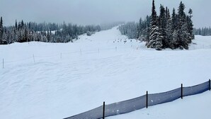 Pista de esquí cubierta de nieve con una valla a lo largo de la base.