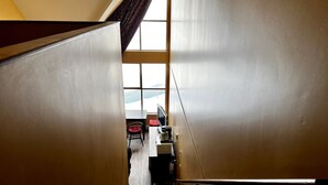 Una escalera estrecha que conduce a una habitación con escritorio, silla y ventana.