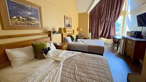Habitación de hotel con dos camas, un escritorio, una silla y un televisor.