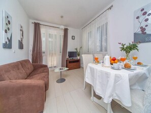 Relax in this stylish living room with a comfortable sofa, dining table, and potted plant.