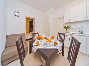 Een ontbijtruimte met een tafel gedekt, compleet met croissants, fruit en sinaasappelsap.