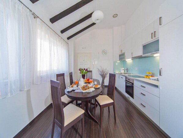 Enjoy meals in this well-lit kitchen and dining area with an oven and round table for four.