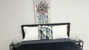 Ein Bett mit dunklem Kopfteil und Fußteil, zwei Kissen und einem Holzrahmen.