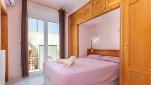 Ein Schlafzimmer mit Bett, Holzschrank, Schreibtisch und Blick ins Freie.