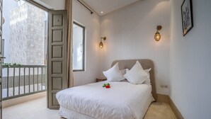 A bedroom with a bed, a window, and a balcony. - Riad Bensaleh 56 (Marrakech)