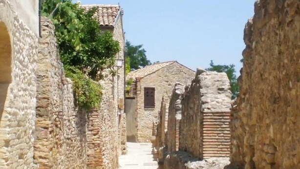 A narrow stone pathway flanked by ancient stone walls, leading to a traditional building with a tiled roof. - Moments of Serenity (Rocca San Giovanni)