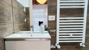 A modern bathroom with a large mirror, a sink, a bidet, and a chandelier. - Moments of Serenity (Rocca San Giovanni)