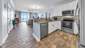 A modern kitchen with white cabinets, stainless steel appliances, and a wooden floor. - 🏖️Beach Front, Great Views-Twin Palms 402🏖️ (Panama City Beach)