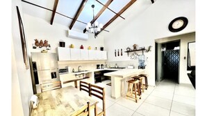 A modern kitchen with white cabinets, a wooden dining table, and a large island. - ATAMI- BEST PRIVATE BEACH HOUSE IN SURF CITY
walk to EL Tunco, El Zonte, Sunzal (La Libertad)
