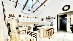 Uma cozinha moderna com armários brancos, uma mesa de jantar de madeira e uma bancada grande.