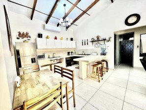 Una cocina moderna con armarios blancos, una mesa de comedor de madera y una isla grande.