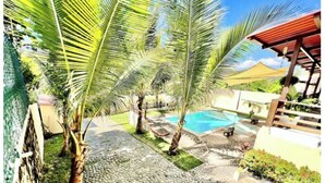 A pool area with palm trees, a stone pathway, and a wooden pergola. - ATAMI- BEST PRIVATE BEACH HOUSE IN SURF CITY
walk to EL Tunco, El Zonte, Sunzal (La Libertad)