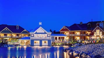 A waterfront hotel with multiple buildings, a reflective pool, and a rocky shoreline.