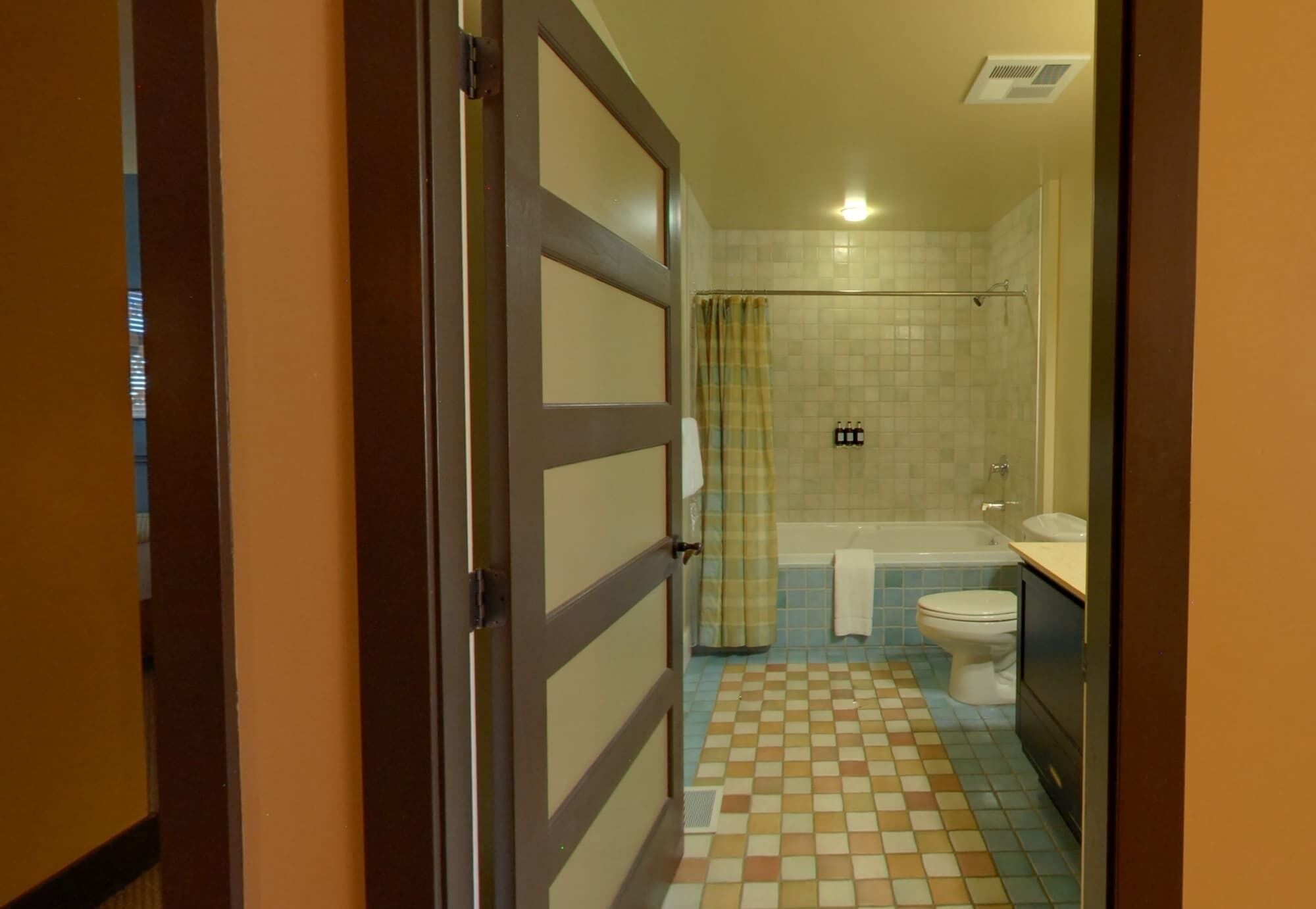 A bathroom with a checkered floor, a shower, a bathtub, and a toilet.