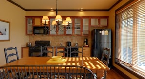 A kitchen with wooden cabinets, a black refrigerator, a stove, and a dining table with chairs. - Hilton Grand Vacations Club Blue Mountain Canada (The Blue Mountains)