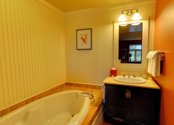 Une salle de bain avec une baignoire, un lavabo, un miroir et un tableau encadré au mur.