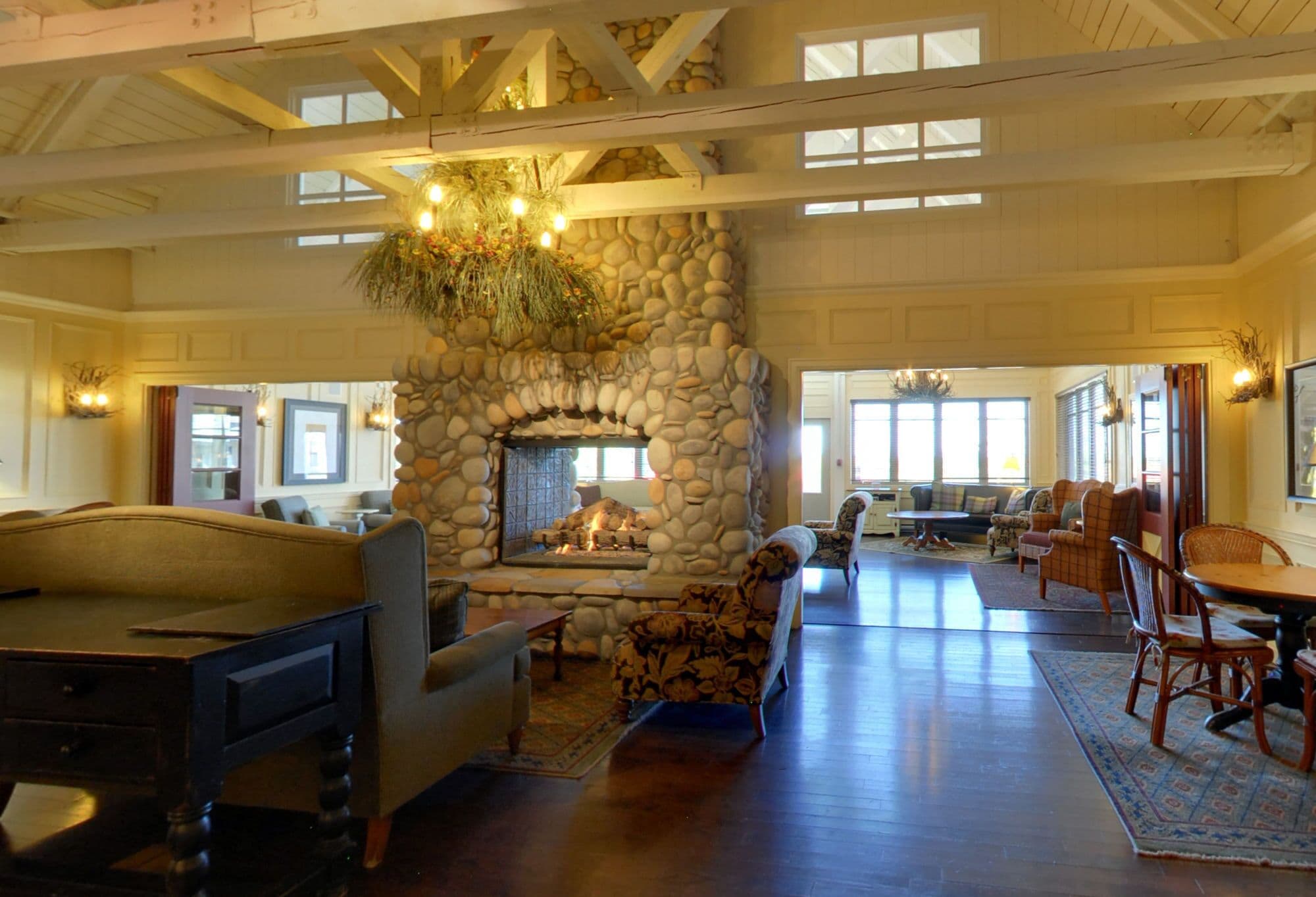 A spacious living room with a stone fireplace, wooden beams, and comfortable seating areas.