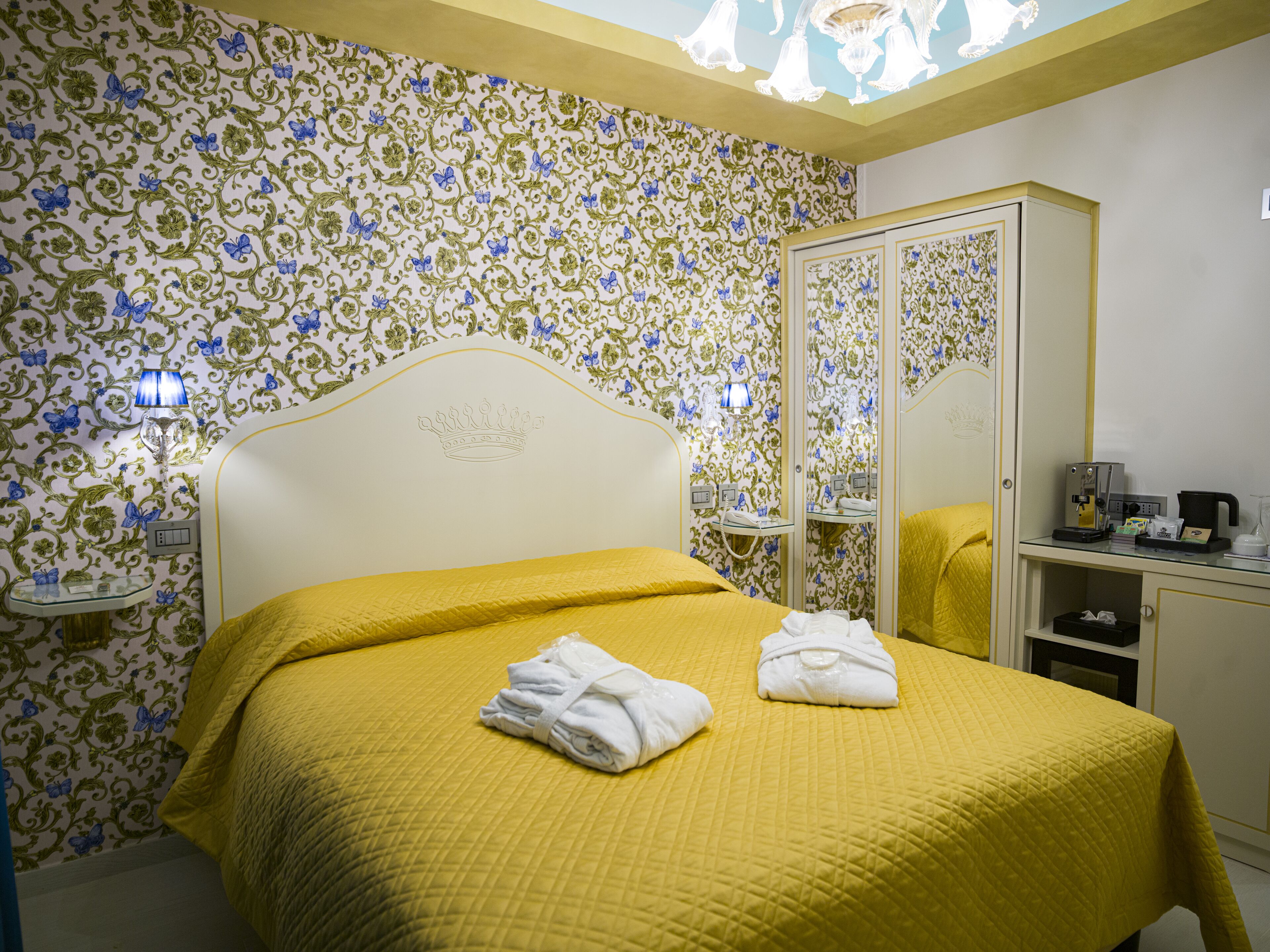 A hotel room with a bed, a mirror, a nightstand, and a wardrobe.