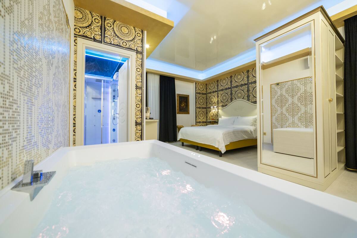 Une salle de bain moderne dotée d’une grande baignoire, d’un espace douche et d’une chambre séparée avec un lit et une coiffeuse.