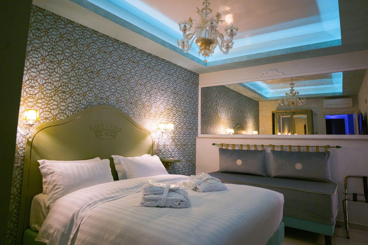 Une chambre à coucher avec un lit, une table de chevet, un miroir et un lustre.