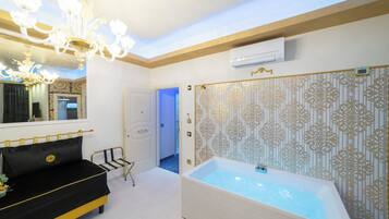 A modern bathroom with a bathtub, a black sofa, a chandelier, and a patterned wall.