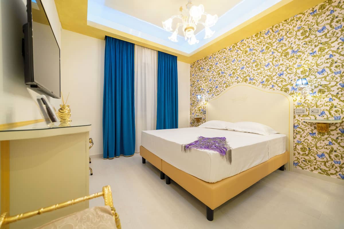 Une chambre d’hôtel avec un lit, une télévision, un bureau et un lustre.