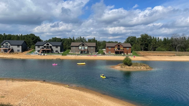 A lakeside property with multiple houses, a sandy beach, and kayaks on the water. - Kokomo Cabin: Cozy Fires, Family Fun & Lake Views (Germantown)