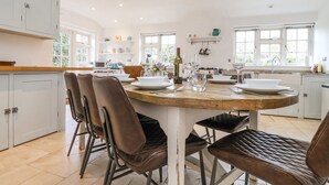 Une cuisine moderne dotée d’un îlot central, de meubles blancs et d’un coin repas avec des chaises marron.