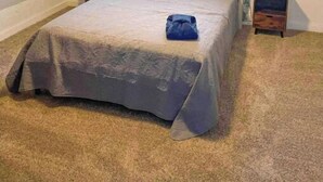 Un dormitorio con una cama individual, un ventilador de techo, una ventana con cortinas y una mesita de noche con lámpara.
