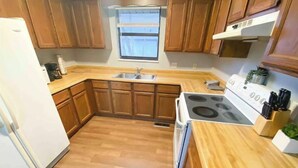 Una cocina compacta con armarios de madera, estufa integrada y un lavamanos.