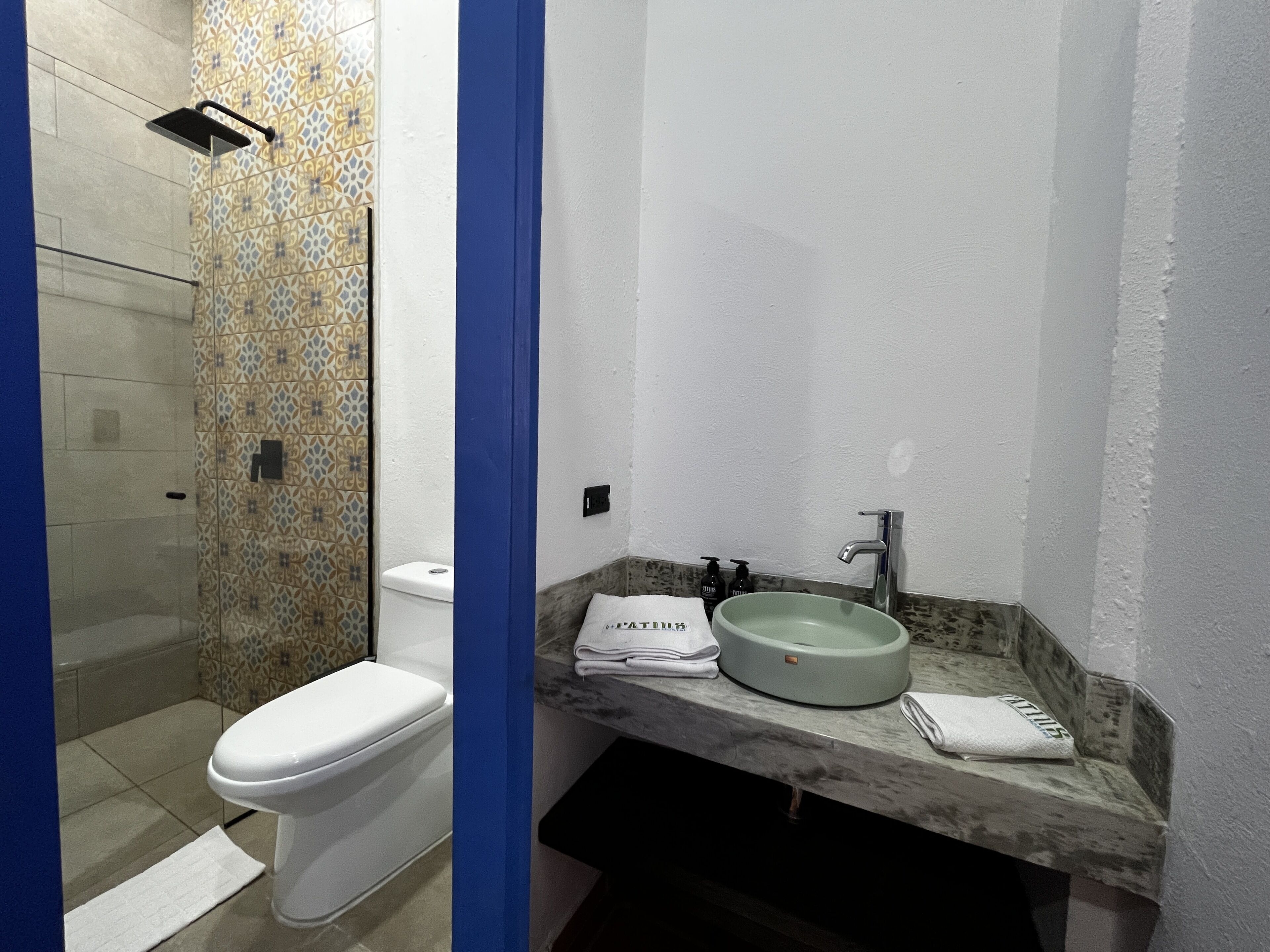 A bathroom with a toilet, a shower, and a sink with a marble countertop.