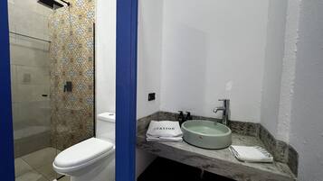 A bathroom with a toilet, a shower, and a sink with a marble countertop.