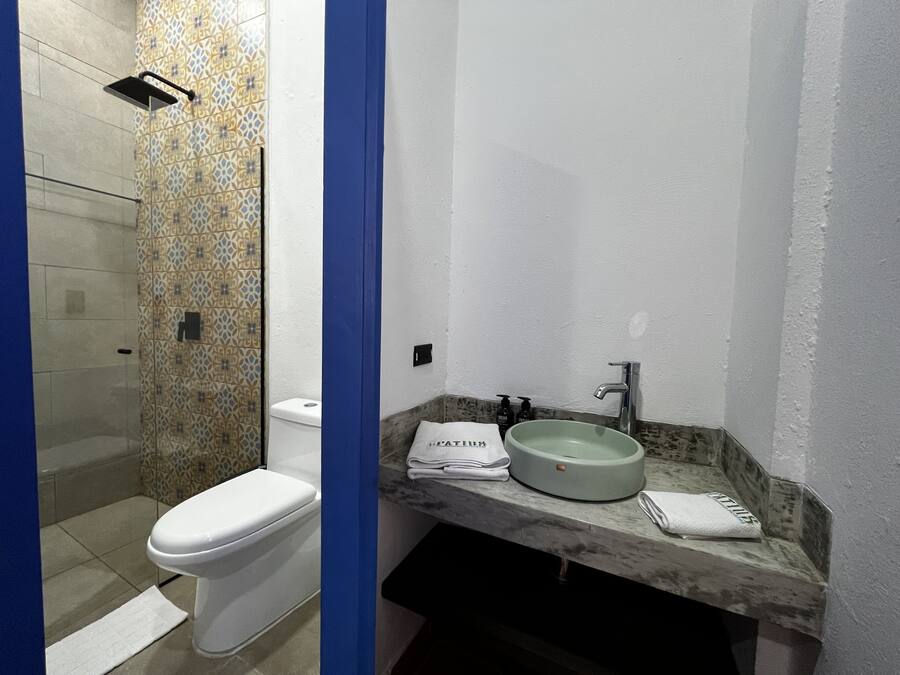 A bathroom with a toilet, a shower, and a sink with a marble countertop.