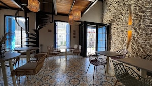 Interior de restaurante con suelo de diseño geométrico, sillas de mimbre y lámparas colgantes de mimbre.