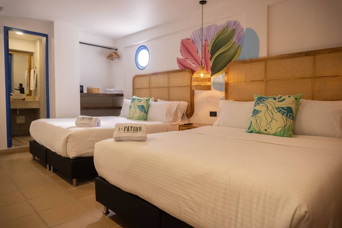 A hotel room with two beds, a bathroom, and a decorative wall.