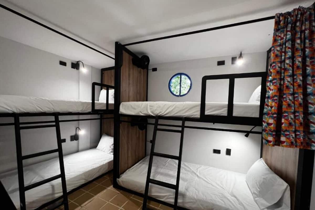 A bunk bed room with two beds, a window, and a curtain.