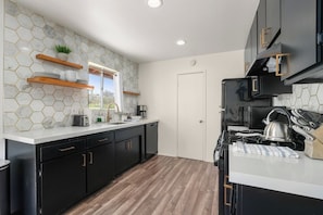 Una cocina moderna con armarios negros, encimera blanca y un salpicadero de azulejos hexagonales.