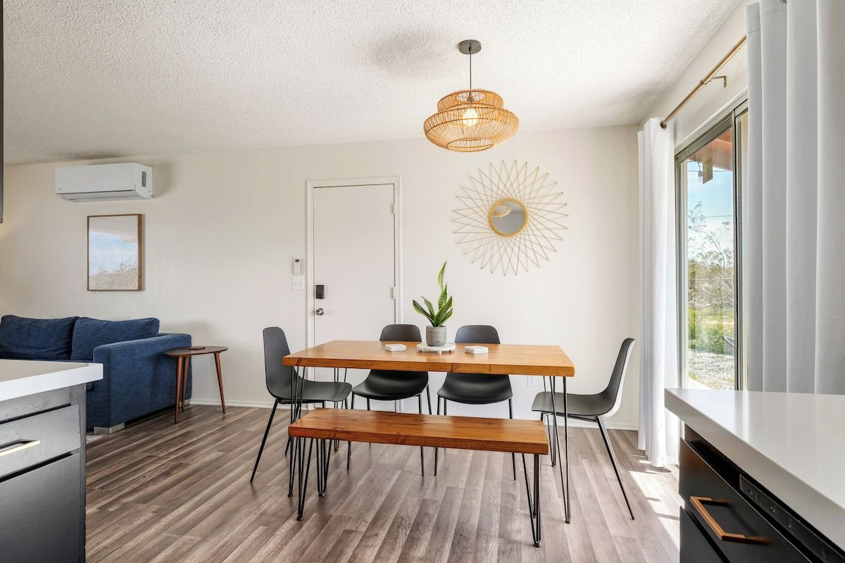 A modern kitchen with a dining area, a blue sofa, and a large window.
