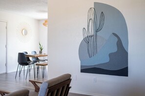 A dining area with a table, chairs, and a wall-mounted mirror.