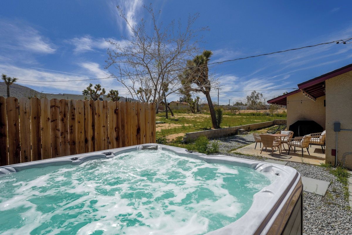 A hot tub with a wooden fence and outdoor furniture in a backyard.