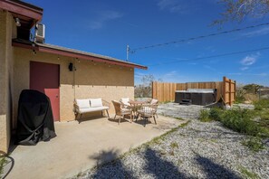 Un patio con mobiliario exterior, una parrilla y un jacuzzi.