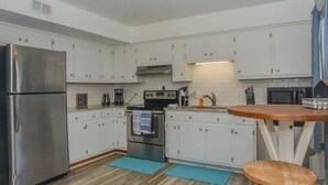 Eine moderne Küche mit weißen Schränken, Edelstahlgeräten und einem Holztisch.