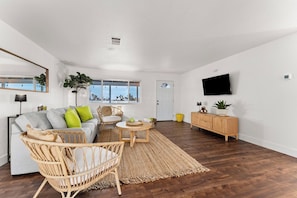 Ein modernes Wohnzimmer mit einer Couch, Sesseln, einem Couchtisch und einem Fernseher.