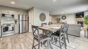 Una cocina moderna con electrodomésticos de acero inoxidable, un comedor con sillas de madera y una sala de estar con chimenea.