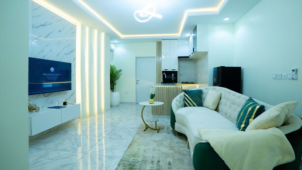 A modern living room with a TV, sofa, and kitchen area.