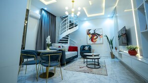 A modern living room with a spiral staircase, a sofa set, a coffee table, and a large painting on the wall.