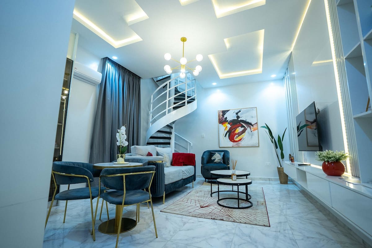 A modern living room with a spiral staircase, a sofa set, a coffee table, and a large painting on the wall.