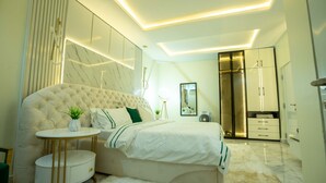 A modern bedroom with a tufted headboard, a round bedside table, a fluffy rug, and built-in wardrobe with LED lighting.