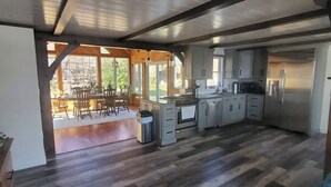 Una cocina moderna con electrodomésticos de acero inoxidable, piso de madera y amplias ventanas con vistas al exterior.