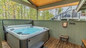 Een hottub op een houten terras met een houten dak en een bordje met de tekst 'Handdoeken'.